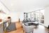 Modern open-concept apartment living room with floor-to-ceiling windows, sleek kitchen, and stylish gray furniture.