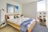 Bright, modern bedroom with a cozy wooden bed, elegant decor, and large window flooding natural light.