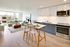 Modern open-concept apartment with a sleek kitchen, stylish breakfast bar, and bright living area featuring floor-to-ceiling windows.