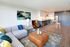 Modern open-concept living area with stylish furniture, vibrant decor, and a sleek kitchen, perfect for cozy gatherings.