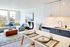 Bright and modern open-concept living space with a cozy sofa, contemporary kitchen amenities, and stylish dining setup.