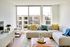 Bright and inviting living room with a large window view, modern furniture, and vibrant decorative pillows.