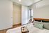 Modern bedroom with cozy bedding, spacious closet, and natural light from large windows.