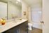 Modern bathroom with sleek dark vanity, marble countertop, and elegant decor.