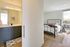 Modern apartment interior featuring a bright bedroom with large windows, stylish bed arrangement, and an elegant ensuite bathroom.
