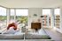 Bright and modern living room with panoramic city views, featuring a cozy gray sofa, stylish red armchair, and chic decor.
