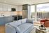 Bright and modern open-concept kitchen with a stylish grey and white color scheme, comfortable seating, stainless steel appliances, and large windows offering city views.