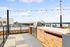Chic rooftop patio with modern grill and stunning urban skyline views, featuring string lights and cozy seating.