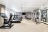 Modern fitness center with state-of-the-art exercise equipment, including treadmills, stationary bikes, and a multi-use weight machine, set against a stylish patterned wall.