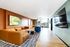 Contemporary living room with stylish leather sectional, vibrant artwork, and a spacious dining area bathed in natural light.