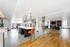 Luxurious open-concept apartment with a modern kitchen, trendy pendant lighting, and a cozy living area featuring a stylish fireplace.