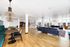 Spacious and modern living area with elegant wooden flooring, stylish pendant lighting, and comfortable seating perfect for social gatherings.