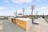 Expansive rooftop terrace with modern BBQ grills, lush planters, and skyline views, perfect for entertaining.