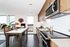 Modern kitchen and dining area with sleek appliances, white countertops, and a stylish table overlooking a scenic city view.