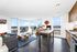 Bright, modern apartment living space with panoramic city views, stylish furnishings, and an inviting open-plan layout.