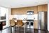 Modern kitchen with sleek wood cabinets, stainless steel appliances, and a cozy breakfast bar with stylish seating, overlooking a scenic view.