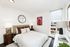Bright modern bedroom with stylish decor, featuring large windows, elegant lamps, and eye-catching artwork.
