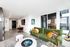 Modern apartment living room with elegant green velvet sofa, vibrant decor, and floor-to-ceiling windows offering a breathtaking view.