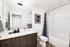 Elegant bathroom with modern vanity, large mirror, and stylish shower curtain, offering a serene retreat.