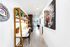 Sleek and stylish apartment hallway with modern artwork and a cozy workspace featuring elegant wooden shelves and vibrant plants.