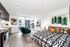 Modern studio apartment with open-concept layout featuring a cozy bedroom area with vibrant decor, compact kitchen with sleek cabinetry, and a stylish living space with large windows offering natural light and city views.