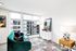 Chic apartment living area with a vibrant green sofa, modern decor, and expansive city views through large windows.