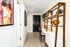 Chic apartment hallway featuring artistic wall decor, modern shelving with plants and decor, and a cozy work nook.