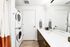 Bright and modern bathroom featuring a sleek vanity with ample storage, and a convenient stacked washer and dryer for efficient living.