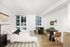 Bright and modern apartment bedroom with large windows, cozy seating area, and a stylish dining nook.