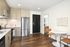 Modern kitchen with stainless steel appliances, chic wood cabinetry, and cozy dining corner featuring sleek chairs and round table.