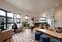 Modern and inviting lounge area with geometric flooring, stylish seating, large windows, and lush greenery.