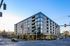 Modern urban apartment building with expansive windows, prime corner location, and street-level retail space.