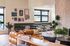 Chic apartment interior showcasing a cozy lounge with a plush leather sofa, stylish wall art, and vibrant potted plants, enhanced by natural light through large windows.