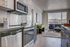 Sleek modern kitchen with stainless steel appliances opening into a bright living room with scenic views.
