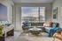 Bright and welcoming living room with modern d&eacute;cor, featuring a plush sectional, textured rug, and expansive window with scenic views.