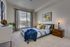 Inviting bedroom with a large window and modern design, featuring a cozy bed with colorful pillows and elegant decor accents.