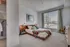 Inviting bedroom with contemporary decor, featuring a cozy bed, elegant lamps, and a large window for natural light.