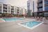 Modern apartment complex featuring a luxurious outdoor pool area with stylish sun loungers and vibrant umbrellas, perfect for relaxation and leisure.
