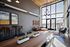 Chic urban living area with high ceilings, large windows, and industrial d&eacute;cor, featuring stylish furniture and modern accents.