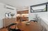 Contemporary kitchen and dining area with sleek wooden cabinets, stainless steel appliances, and a round wooden table with stylish black chairs.