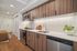Modern kitchen with sleek wooden cabinets, stainless steel appliances, and bright under-cabinet lighting. Features a stylish backsplash and elegant plant decor.