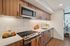 Modern kitchen with sleek wood cabinetry, stainless steel appliances, and elegant white tiles.