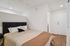 Cozy bedroom with a stylish black headboard, elegant striped bedding, and warm wood flooring, offering a welcoming retreat.