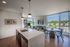 Modern open-concept apartment interior with a stylish kitchen island, cozy living area, and expansive windows offering scenic views.
