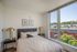 Bright and inviting bedroom with elegant decor, featuring large windows offering scenic city views and abundant natural light.