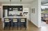 Modern apartment kitchen featuring sleek cabinetry, a stylish island with seating, and a view of a cozy bedroom and balcony.