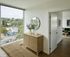 Chic apartment interior featuring a cozy hallway with a wooden cabinet, large window offering scenic views, and a glimpse into a stylish living area.