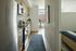 Contemporary apartment kitchen with sleek appliances and wooden cabinetry leads to a bright bedroom with modern furnishings.