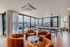 Spacious and stylish living area featuring plush orange chairs, large windows with scenic views, and a modern dining space with chic pendant lighting.