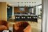 Contemporary living space with chic orange velvet chairs, stylish pendant lighting, and a cozy fireplace setting next to a dining area.